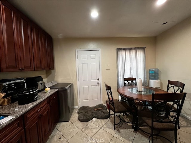 kitchen with washer / dryer, light tile patterned floors, and light stone counters