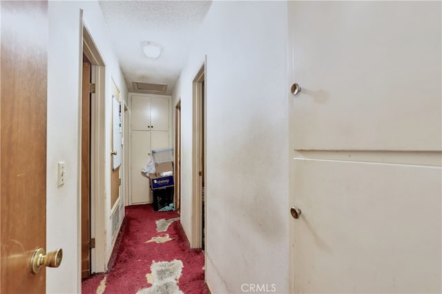 corridor with dark colored carpet and a textured ceiling