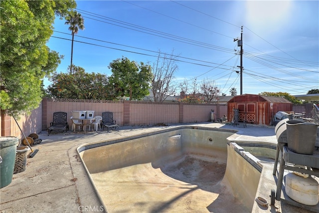 view of pool featuring a shed and a patio area