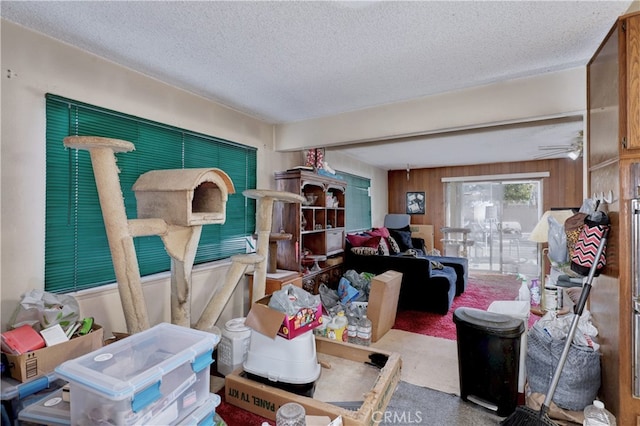 miscellaneous room featuring carpet flooring, a textured ceiling, ceiling fan, and wood walls