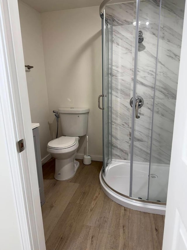 bathroom featuring a shower with shower door, vanity, toilet, and hardwood / wood-style flooring