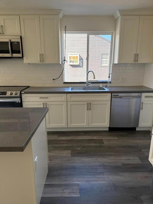 kitchen featuring white cabinets, appliances with stainless steel finishes, decorative backsplash, sink, and dark hardwood / wood-style floors