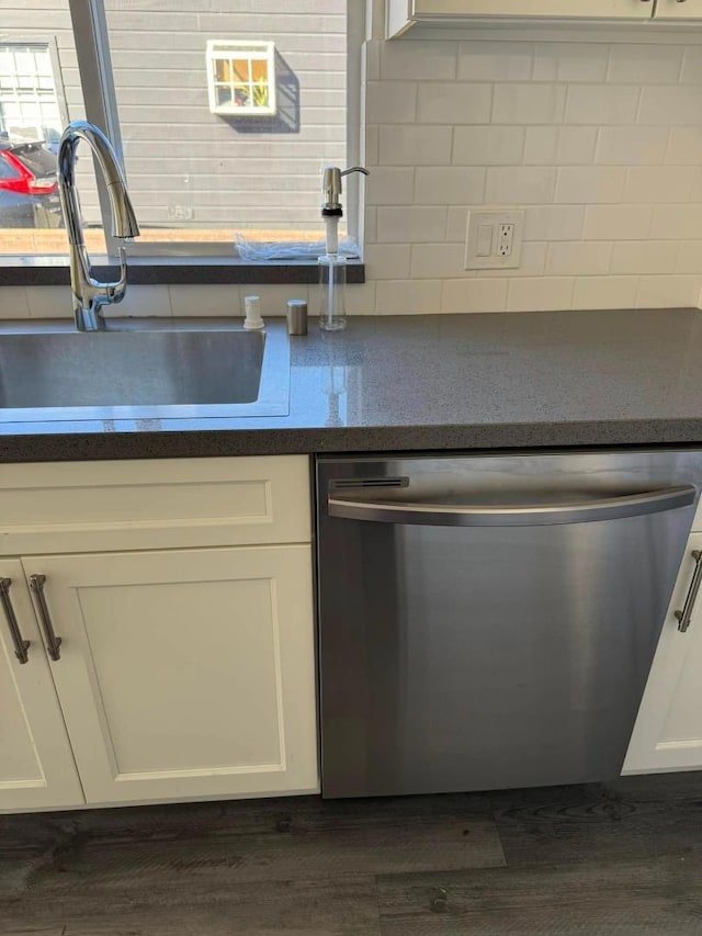 kitchen featuring tasteful backsplash, stainless steel dishwasher, sink, white cabinetry, and dark hardwood / wood-style flooring