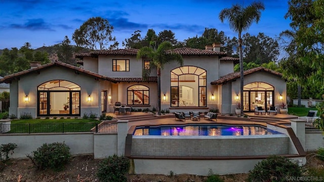 back house at dusk featuring french doors and a patio