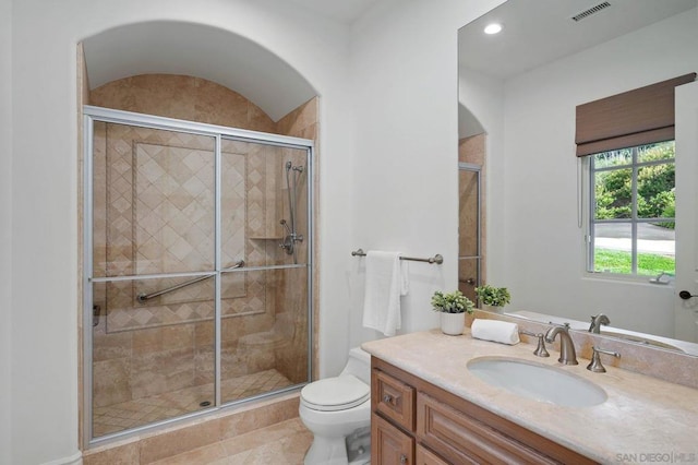 bathroom with tile patterned flooring, vanity, a shower with shower door, and toilet