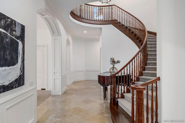 foyer featuring crown molding and a towering ceiling