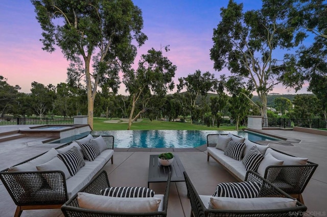 pool at dusk featuring outdoor lounge area, a patio area, and an in ground hot tub