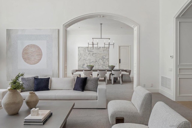 carpeted living room featuring a notable chandelier and ornamental molding