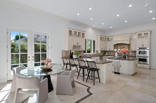 kitchen with a center island, dark stone counters, ornamental molding, tasteful backsplash, and stainless steel appliances