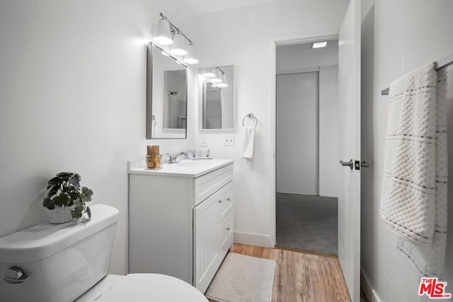 bathroom with hardwood / wood-style flooring, vanity, and toilet