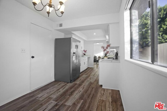 kitchen with white cabinetry, dark wood-type flooring, high end fridge, and an inviting chandelier