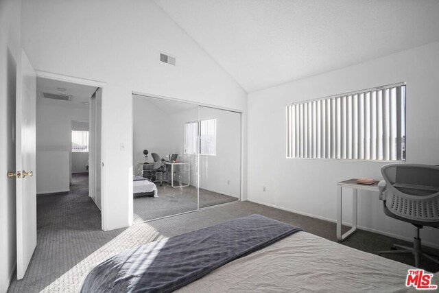 bedroom featuring high vaulted ceiling, a closet, and dark colored carpet