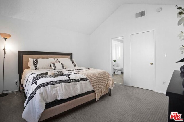 carpeted bedroom with connected bathroom and high vaulted ceiling