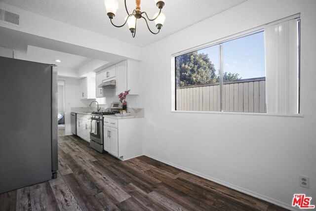 kitchen with white cabinetry, stainless steel appliances, dark wood-type flooring, and a textured ceiling