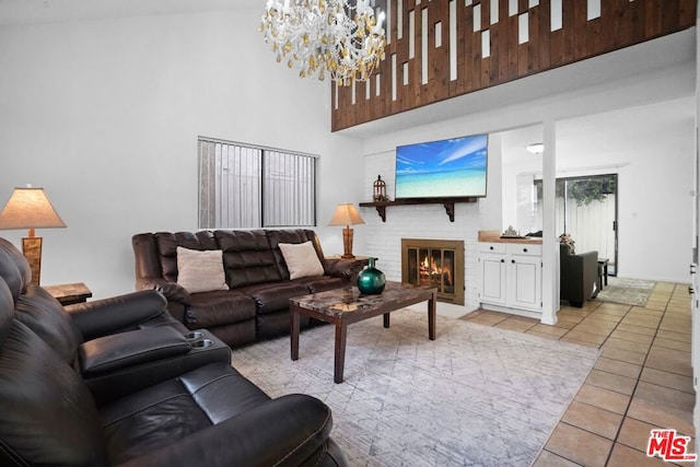 tiled living room featuring a notable chandelier, a brick fireplace, and a high ceiling