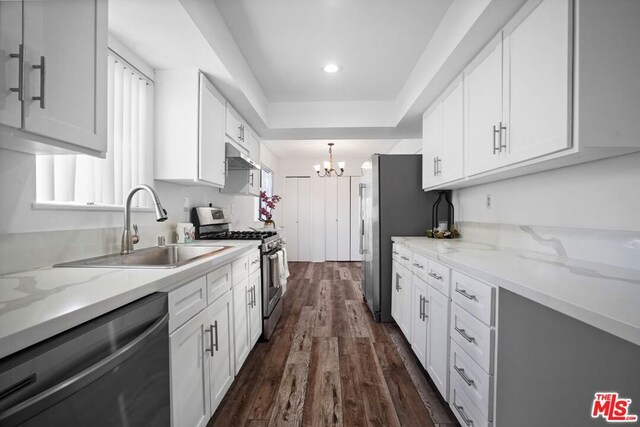 kitchen with sink, light stone countertops, white cabinets, and appliances with stainless steel finishes