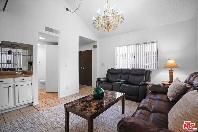 living room featuring light tile patterned floors, a notable chandelier, high vaulted ceiling, and sink