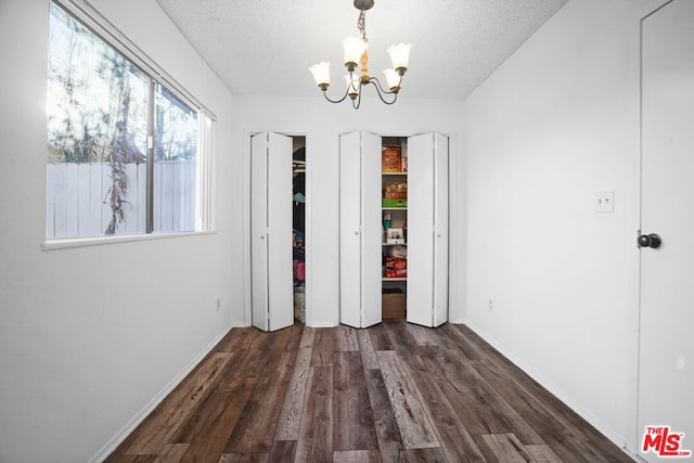 interior space featuring dark wood-type flooring, a chandelier, and a textured ceiling