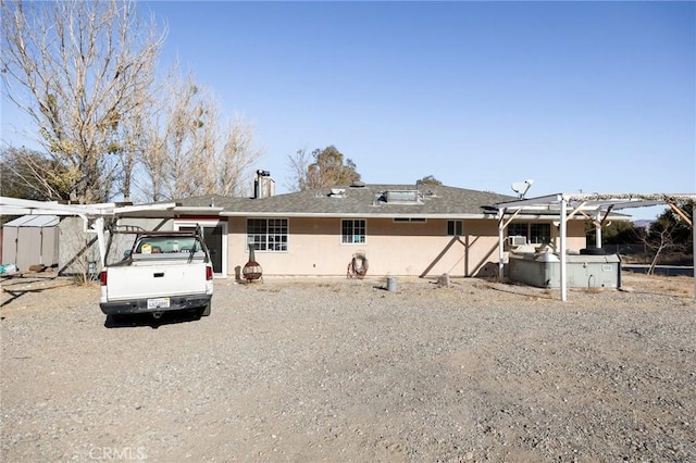 back of property with a carport and a storage shed