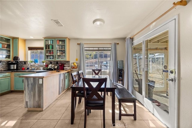 kitchen with butcher block counters, sink, tasteful backsplash, green cabinets, and light tile patterned flooring