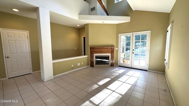 unfurnished living room with light tile patterned flooring, high vaulted ceiling, and french doors