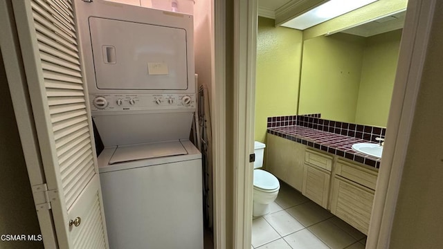 laundry room with light tile patterned flooring, sink, ornamental molding, and stacked washer / dryer