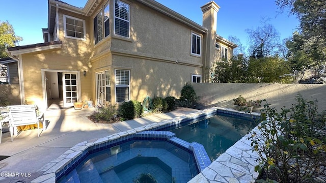 back of property featuring a patio area and an in ground hot tub