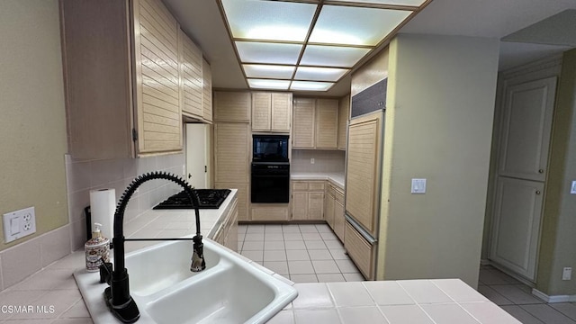 kitchen featuring tile counters, light brown cabinets, sink, light tile patterned floors, and black appliances