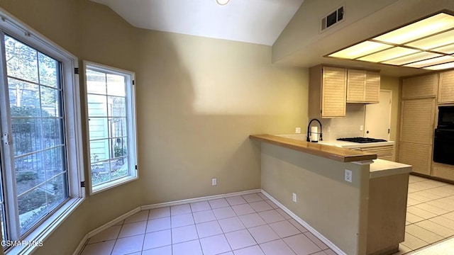 kitchen featuring kitchen peninsula, light tile patterned floors, black appliances, and vaulted ceiling