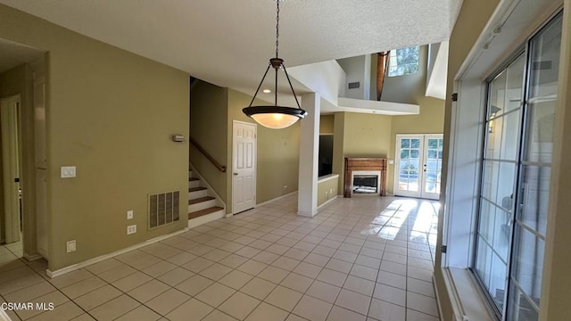 interior space with a textured ceiling, french doors, light tile patterned floors, and a high ceiling