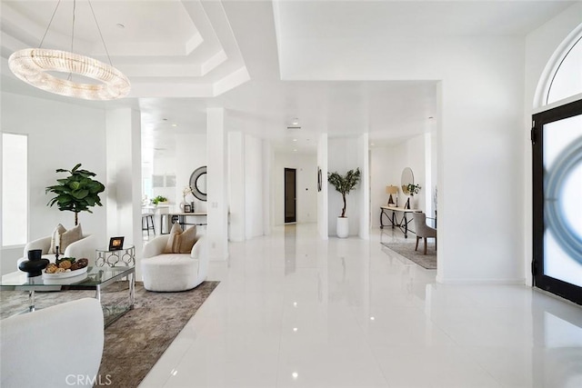 foyer entrance featuring a raised ceiling and baseboards