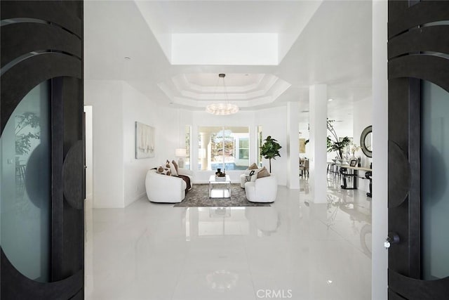 entrance foyer with a chandelier, arched walkways, and a raised ceiling