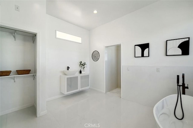 full bath with baseboards, a spacious closet, a soaking tub, and recessed lighting