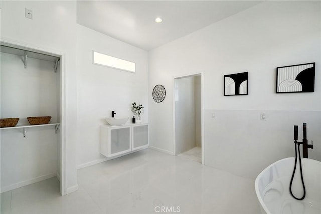 full bathroom with a soaking tub, baseboards, a spacious closet, and recessed lighting