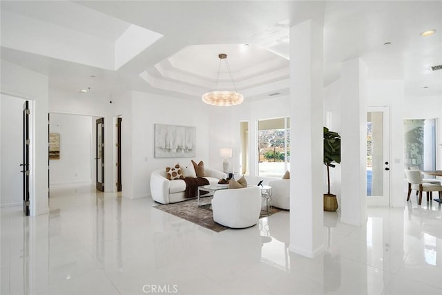 living room with a towering ceiling, visible vents, marble finish floor, a tray ceiling, and an inviting chandelier