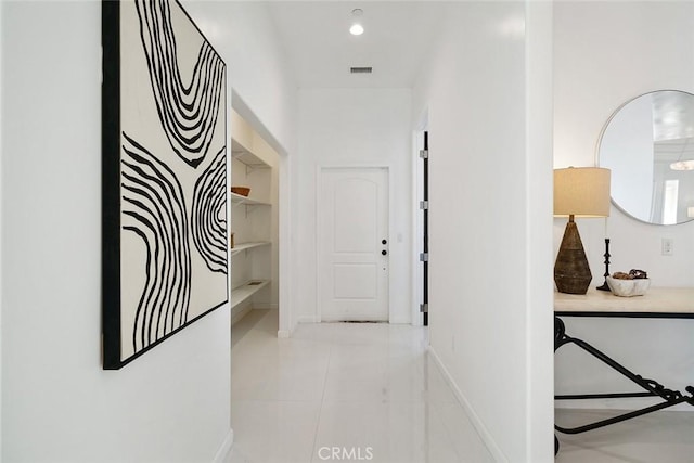 hall featuring baseboards, visible vents, and light tile patterned flooring
