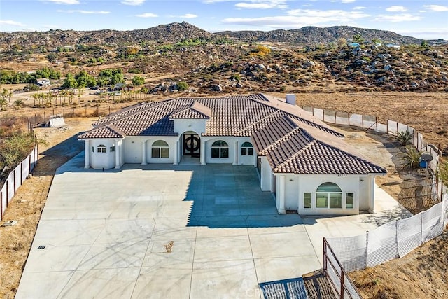 view of front of property featuring fence private yard, a tile roof, stucco siding, and a mountain view