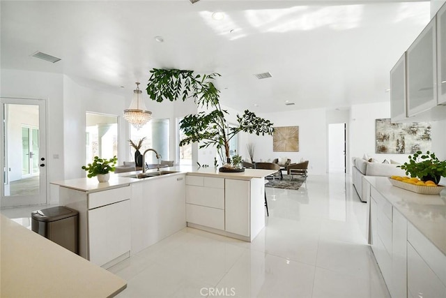 kitchen with light countertops, modern cabinets, a sink, and visible vents