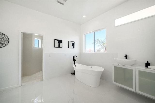 bathroom featuring visible vents, a freestanding tub, vanity, and recessed lighting