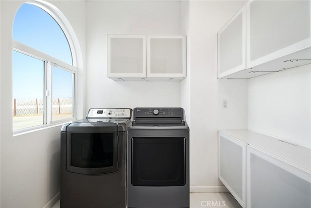 clothes washing area featuring cabinet space, baseboards, and independent washer and dryer