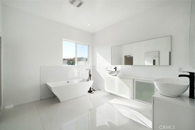 bathroom featuring a sink, double vanity, baseboards, visible vents, and a freestanding tub
