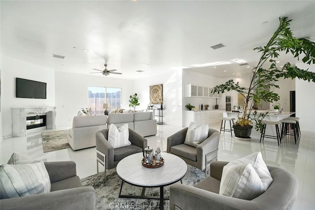 living area featuring ceiling fan, visible vents, and a high end fireplace