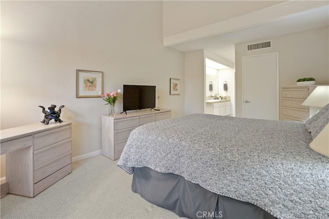 bedroom featuring light colored carpet and ensuite bath