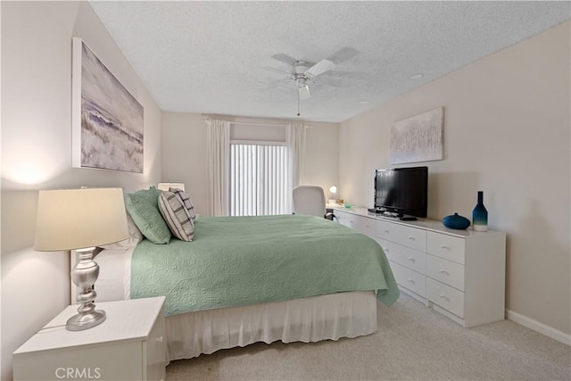 bedroom featuring ceiling fan, light colored carpet, and a textured ceiling