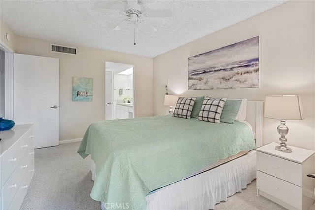 carpeted bedroom with ceiling fan, a textured ceiling, and ensuite bathroom