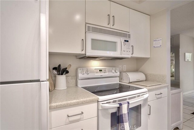 kitchen with light tile patterned floors, white cabinets, and white appliances