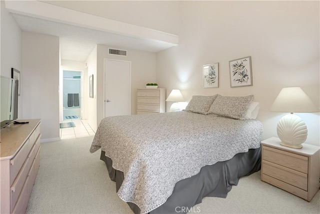 bedroom with light colored carpet and ensuite bathroom