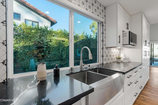 kitchen featuring sink, white cabinetry, backsplash, and light wood-type flooring