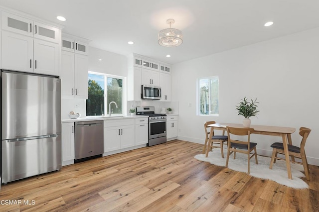 kitchen featuring light wood-type flooring, stainless steel appliances, white cabinetry, and sink