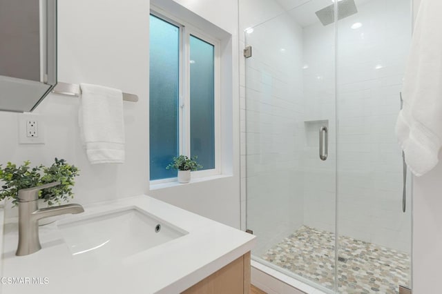 bathroom featuring walk in shower, vanity, and a healthy amount of sunlight